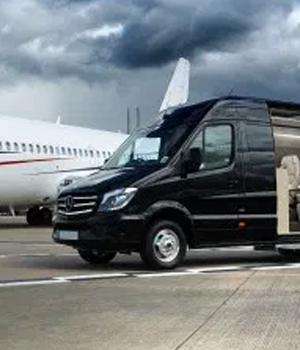 A sleek black bus waiting outside the airport terminal, ready to transport travelers to their destinations, with luggage being loaded on board.